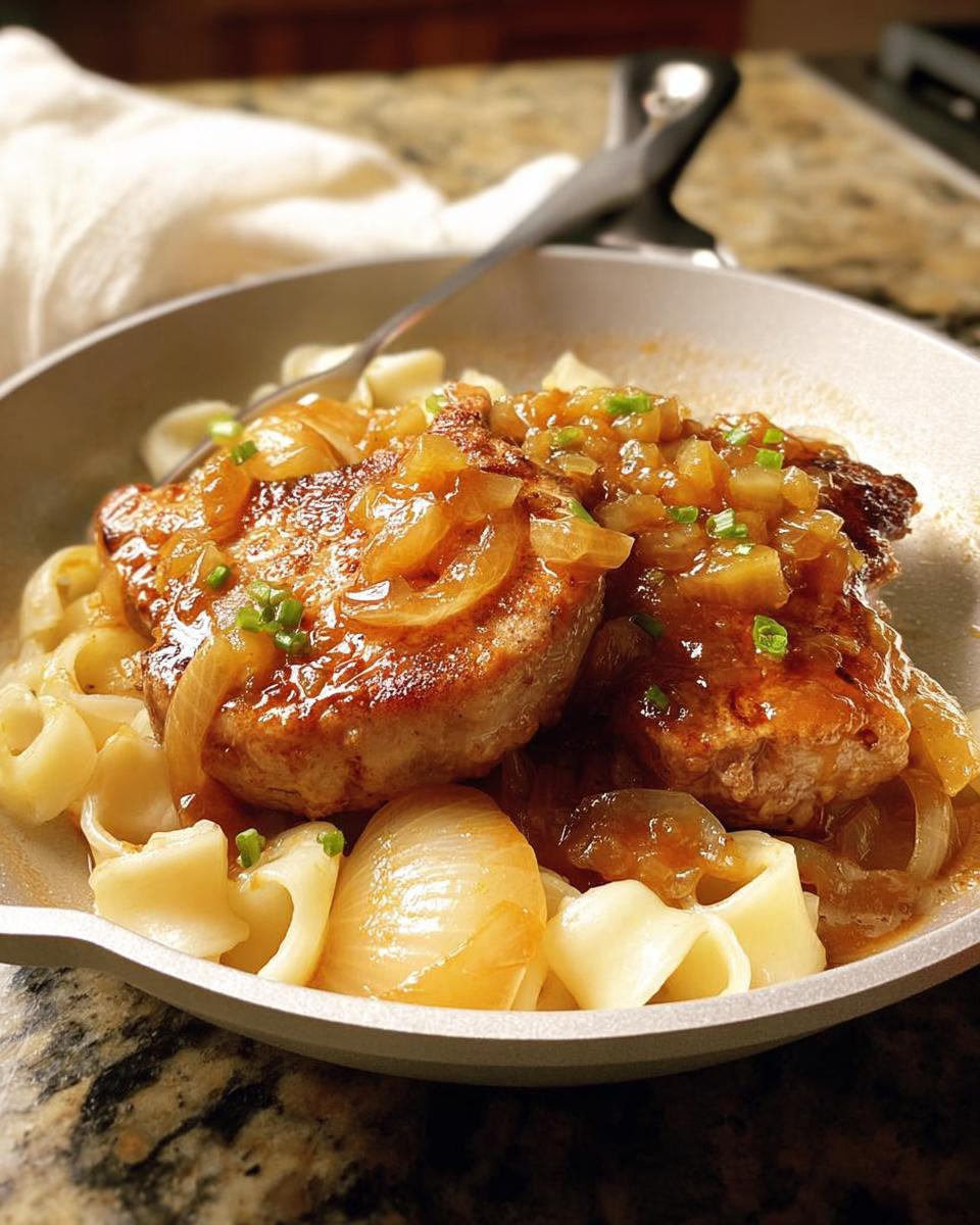 Close-up of 10-Ingredient Pork Chops Recipe served over wide egg noodles with a rich onion gravy.
