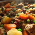 Close-up of a hearty 20 minute stuffing recipe with chunks of meat, potatoes, carrots, peas, and cranberries.