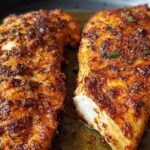Close-up of two perfectly cooked air fryer chicken breasts with a flavorful spice rub.