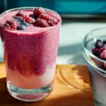 A vibrant berry smoothie in a glass, topped with fresh raspberries and blueberries, perfect for breakfast ideas recipes.