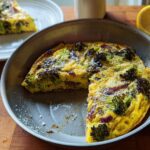 A slice of broccoli and red onion frittata in a skillet, part of 25 Genius Egg Recipes Ideas for Busy Weeknights.