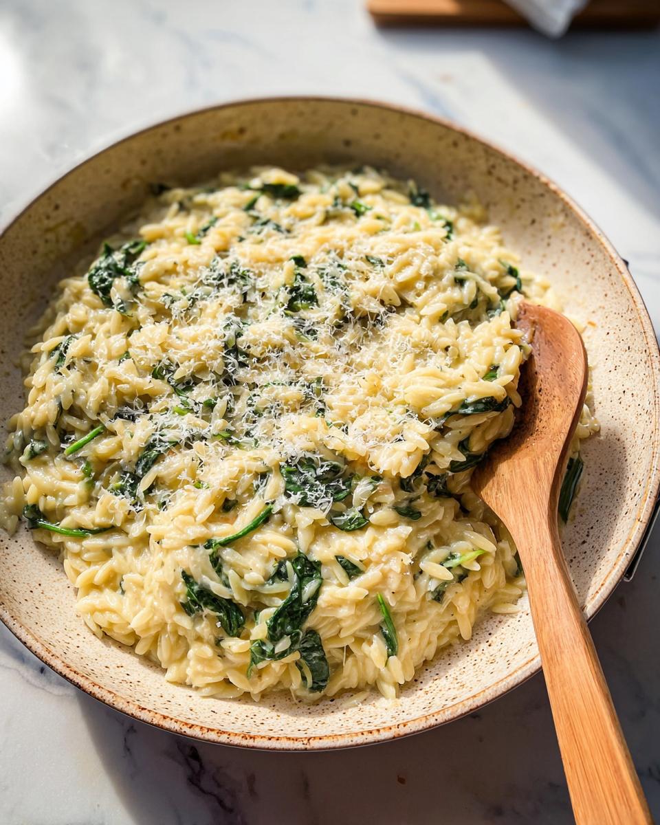A close-up of creamy spinach orzo, a delicious veggie side dish, topped with grated Parmesan cheese.