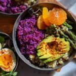 A vibrant bowl featuring purple rice, sliced soft-boiled eggs, avocado, asparagus, and orange slices. Part of The Ultimate Egg Recipes Guide.