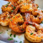 Close-up of perfectly cooked garlic butter shrimp, seasoned with herbs, ready to be served.
