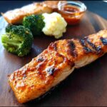 A perfectly grilled salmon fillet with char marks, served with broccoli and mashed potatoes, part of 12-Ingredient Salmon Recipes.