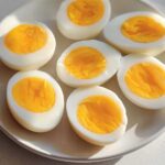 Six perfectly cooked hard-boiled eggs, halved, revealing bright yellow yolks, ready for healthy meals recipes meal prep.