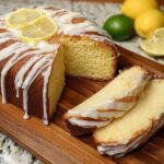 A delicious lemon cake recipe, drizzled with icing and topped with lemon slices, with two slices cut and ready to serve.