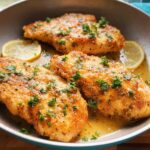 Golden brown pan-seared chicken breasts with lemon slices and fresh parsley, a healthy meal idea.