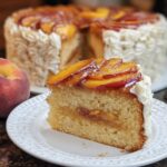 A slice of delicious peach cake with creamy frosting and glazed peach slices on top, part of The Ultimate Cake Ideas Recipes Guide for Beginners.