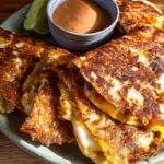 Golden brown quesadillas cut into wedges, served with a side of dipping sauce and lime wedges, perfect for Restaurant-Style Taco Tuesday Recipes at Home.