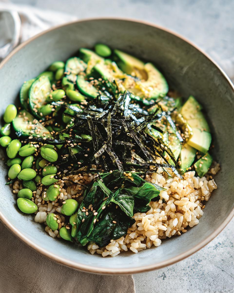 A vibrant rice bowl with brown rice, avocado slices, edamame, spinach, and seaweed, perfect for beginner rice bowl recipes.