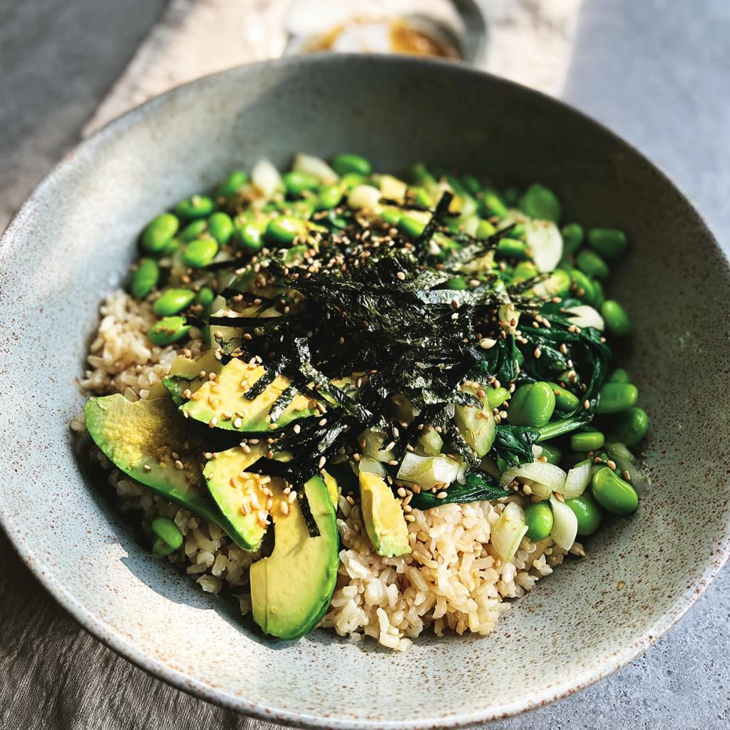A vibrant rice bowl topped with sliced avocado, edamame, greens, nori, and sesame seeds, part of The Ultimate Rice Bowls Recipes Guide.
