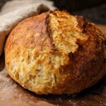 A rustic loaf of rosemary sourdough bread, golden brown with a crackled crust, perfect for healthy meals recipes.