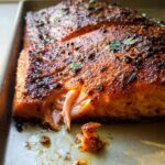 A close-up of a perfectly cooked salmon fillet with a crispy, seasoned crust, ready to be served in a recipe.