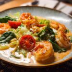 Close-up of a creamy shrimp recipe dish with cherry tomatoes and spinach.