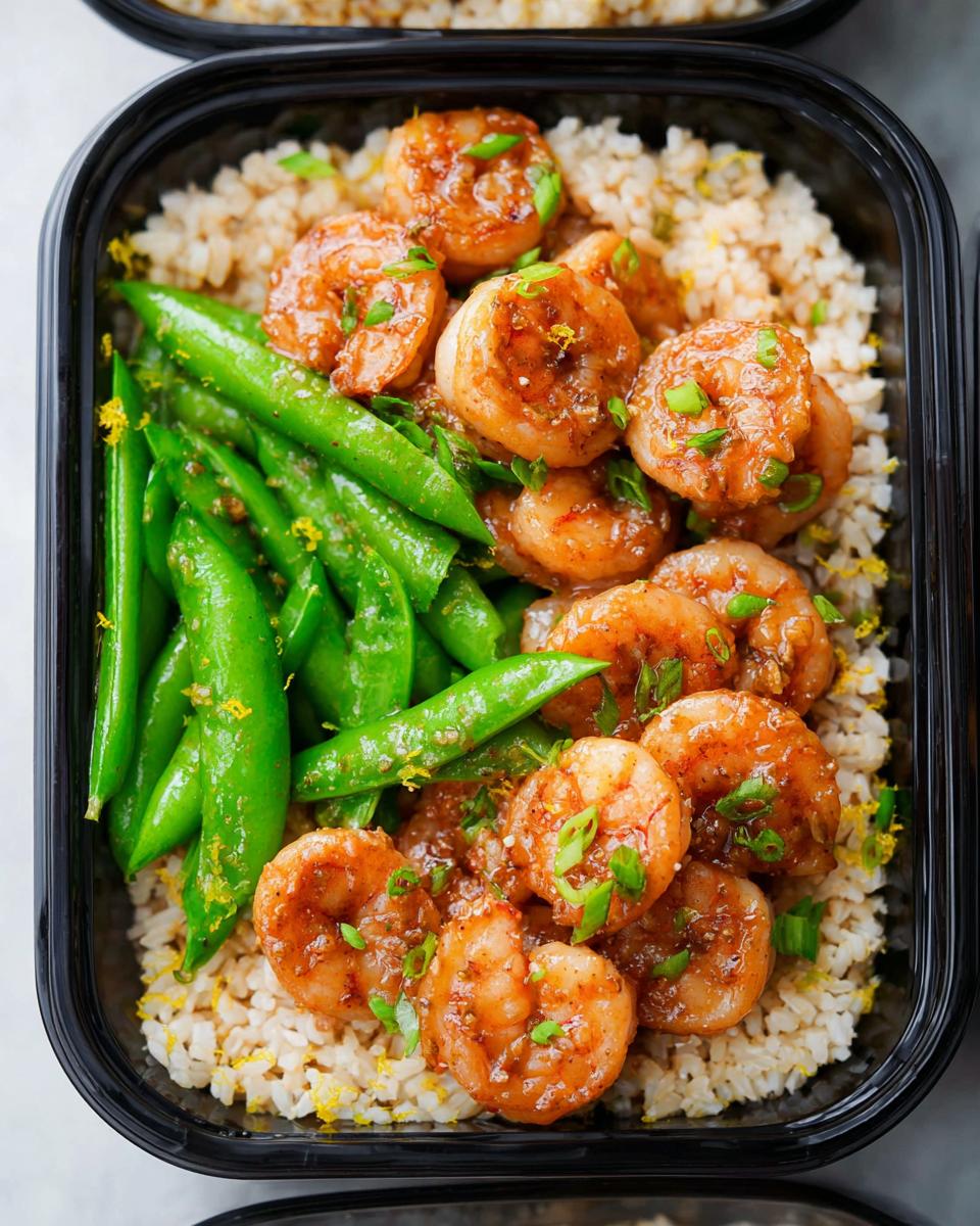 Meal prep container filled with brown rice, glazed shrimp, and snap peas, perfect for shrimp recipes meal prep.