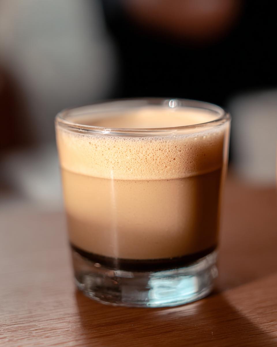 A close-up of a Starbucks espresso shot in a glass, showing rich crema on top.