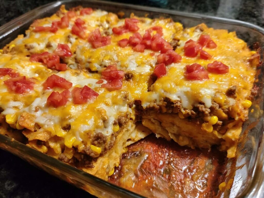 A close-up of a cheesy Taco Tuesday casserole with ground beef, corn, and diced tomatoes.