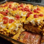 A close-up of a cheesy Taco Tuesday casserole with ground beef, corn, and diced tomatoes.