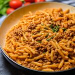 A close-up of a pan filled with Creamy High Protein Beef Pasta, garnished with fresh herbs.