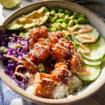 A delicious Crispy Salmon and Rice Bowl featuring glazed salmon, avocado, edamame, cucumber, and red cabbage.