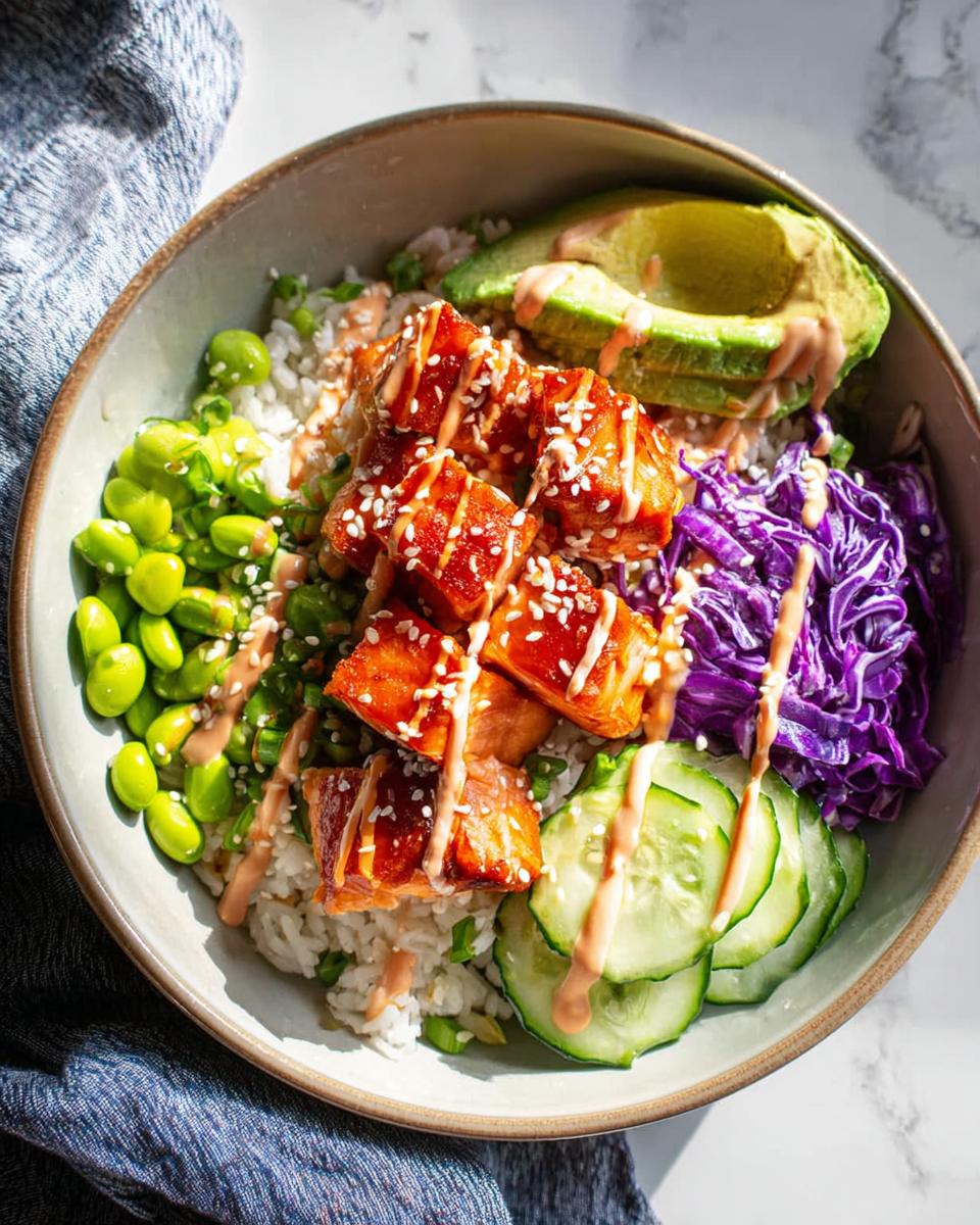 A vibrant Crispy Salmon and Rice Bowl featuring glazed salmon, avocado, edamame, cucumber, and red cabbage.