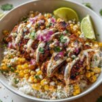 A vibrant Easy Street Corn Chicken Bowl featuring grilled chicken, corn, rice, crumbled cheese, red onion, and lime wedges.