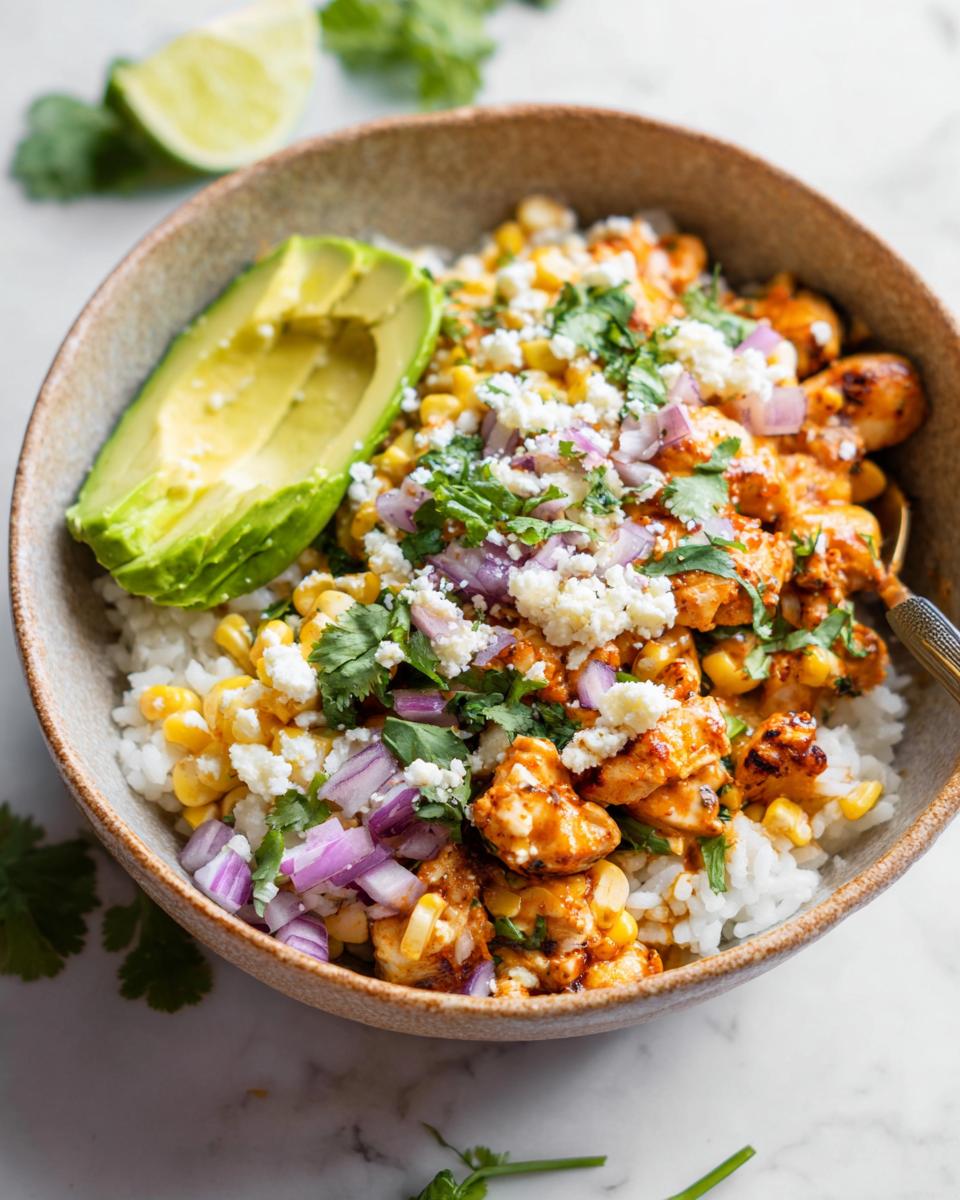 A vibrant Easy Street Corn Chicken Bowl featuring rice, seasoned chicken, corn, avocado, red onion, cilantro, and crumbled cheese.