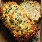 A close-up of a delicious Garlic Parmesan Chicken Meatloaf topped with melted cheese and fresh parsley.