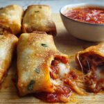 Golden brown HIGH PROTEIN Pepperoni Pizza Rolls filled with melted cheese and pepperoni, served with marinara sauce.