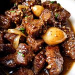 Close-up of tender High Protein Slow Cooker Garlic Butter Beef Bites with onions in a rich sauce.