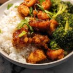 A close-up of a Honey Garlic Pork Rice Bowl with fluffy white rice, crispy glazed pork pieces, and steamed broccoli.