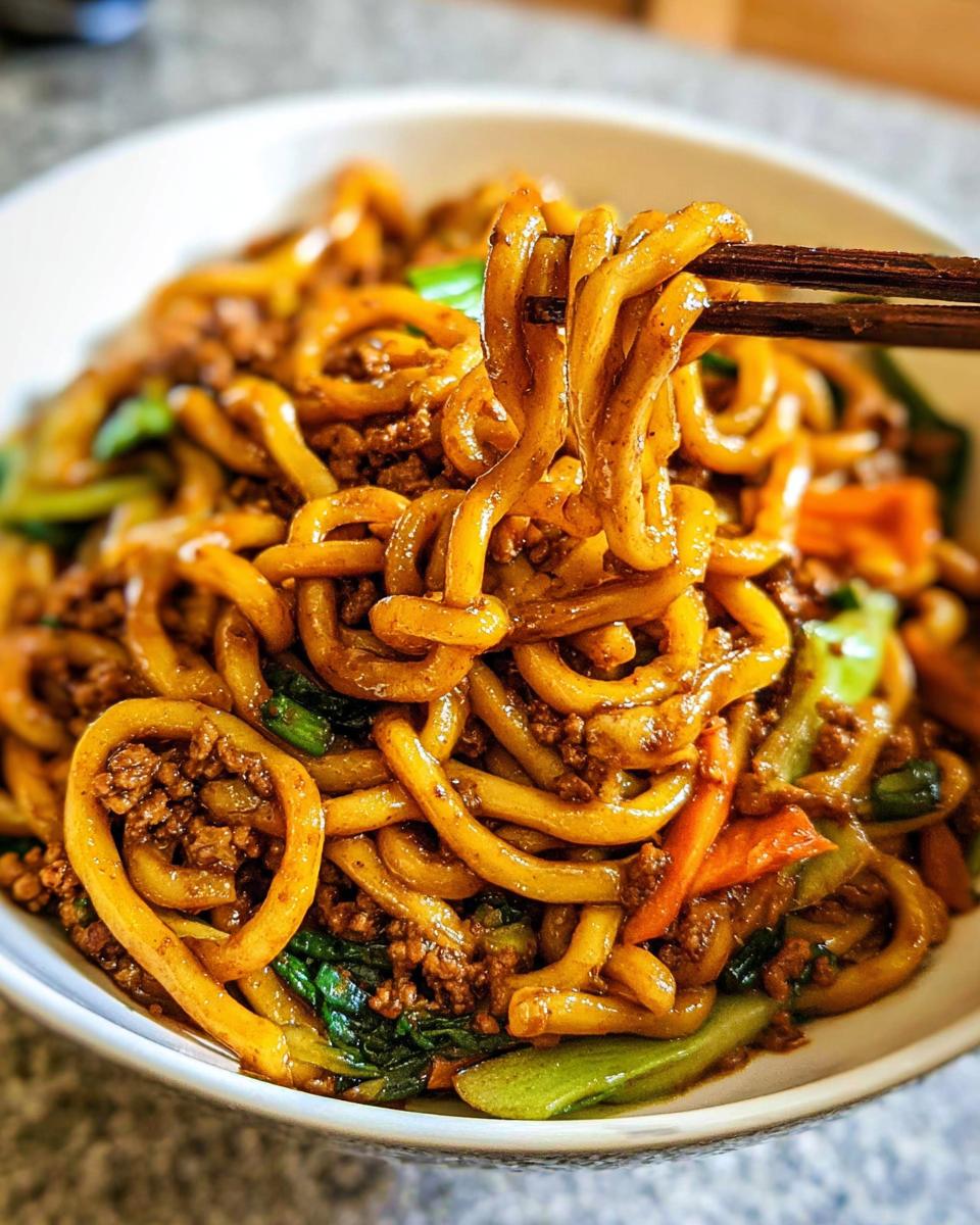 Close-up of a bowl of Irresistible Yaki Udon Noodles with ground meat, bok choy, and carrots.