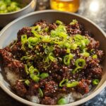 A close-up of a Korean Ground Beef Bowl with white rice, topped with savory ground beef and fresh green onions and sesame seeds.