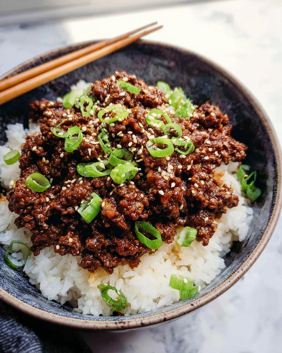 A close-up of a Korean Ground Beef Bowl, featuring seasoned ground beef over white rice, garnished with green onions and sesame seeds.