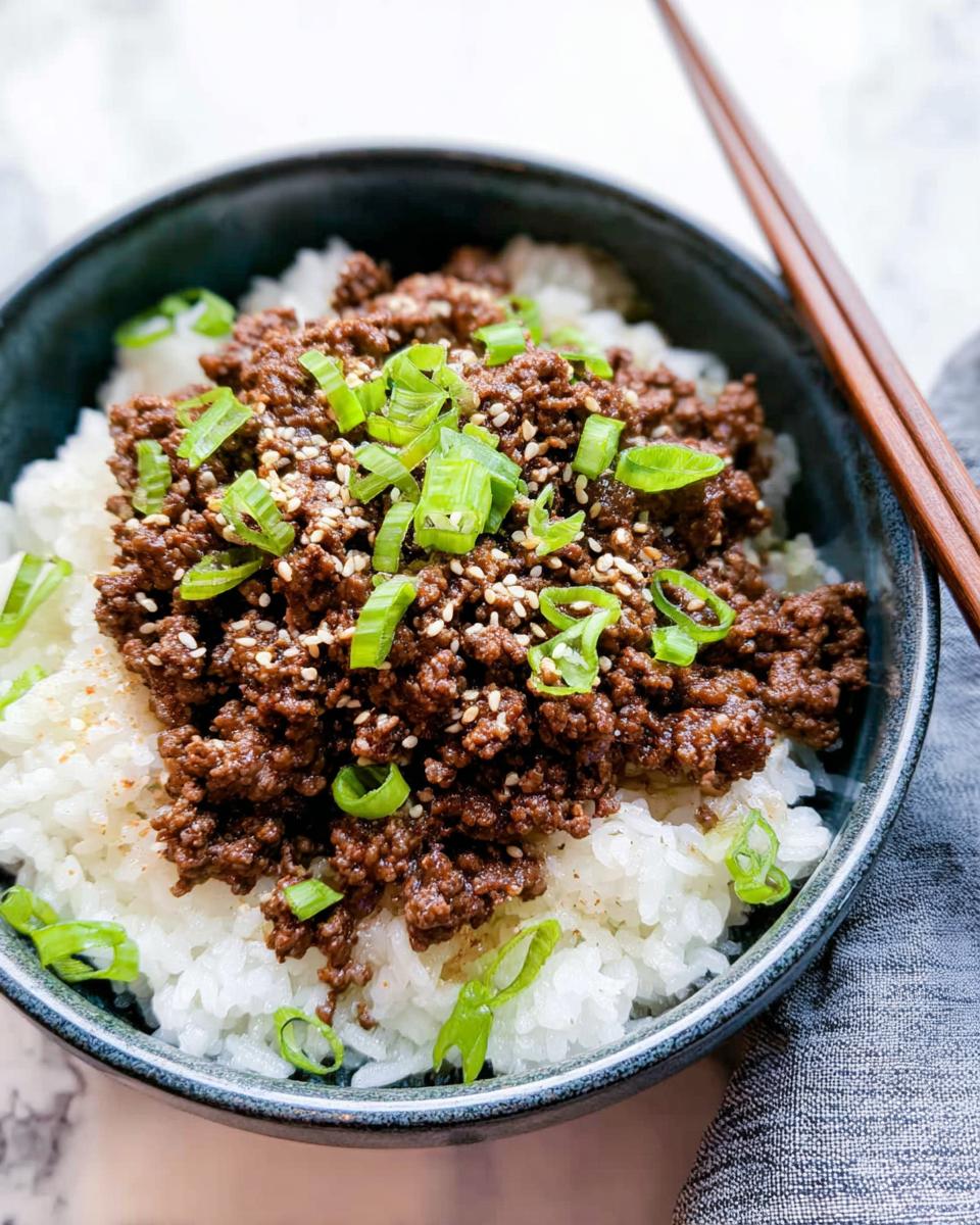 Close-up of a Korean Ground Beef Bowl, featuring seasoned ground beef over white rice, topped with chopped green onions and sesame seeds.