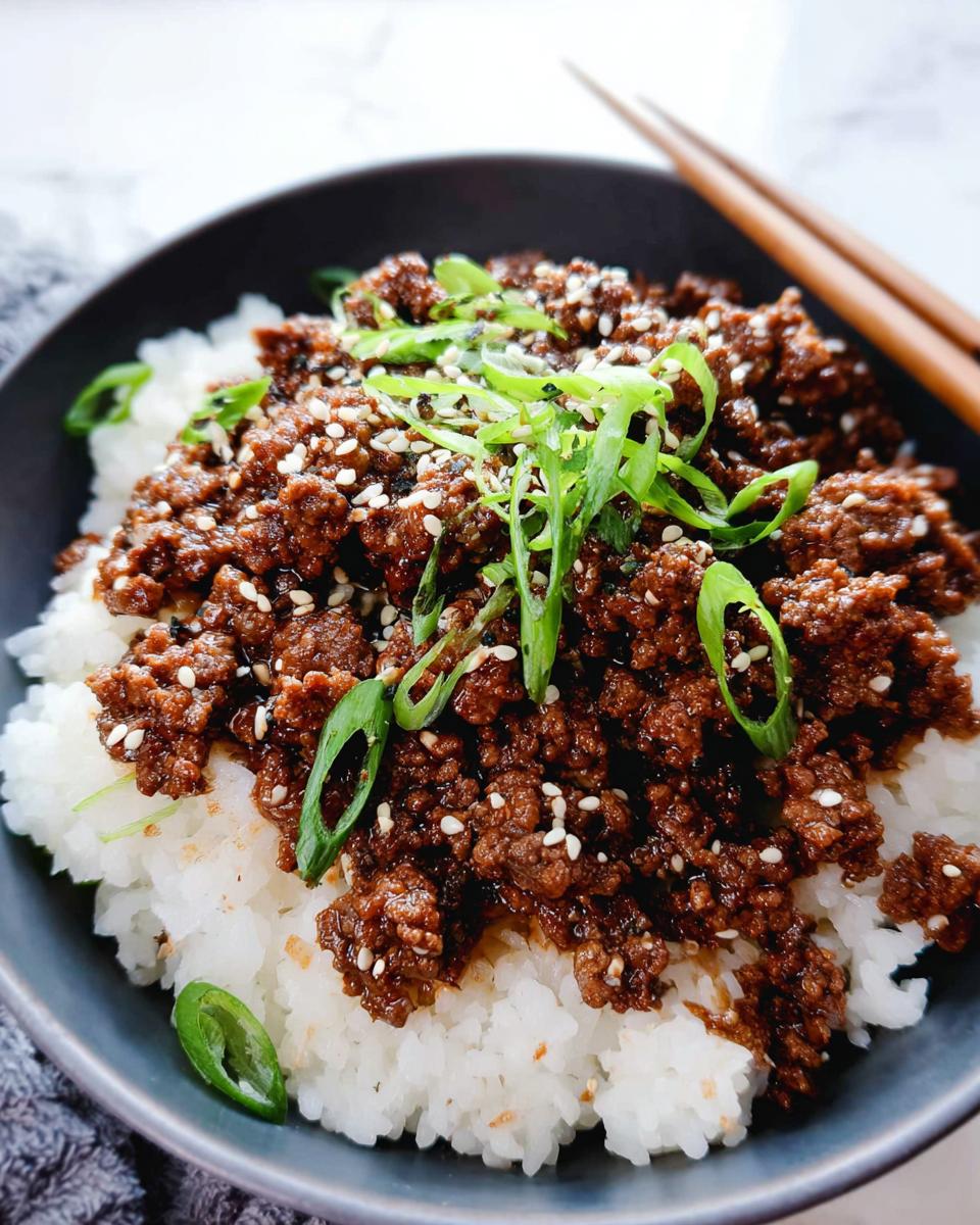 A close-up of a Korean Ground Beef Bowl, featuring seasoned ground beef over white rice, topped with sesame seeds and green onions.