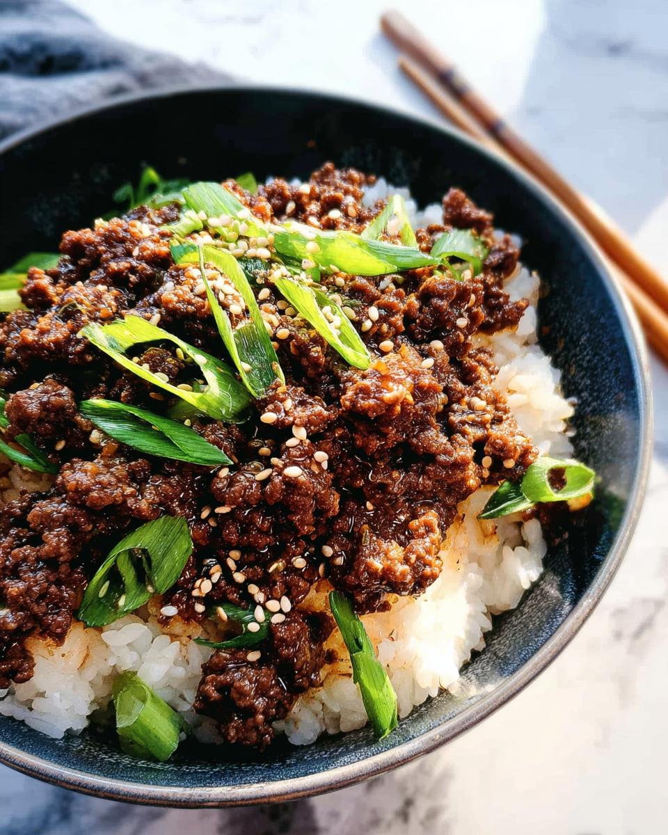 A close-up of a Korean Ground Beef Bowl, featuring savory ground beef over fluffy white rice, topped with green onions and sesame seeds.