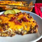 A slice of Low-Carb Bacon Cheeseburger Casserole topped with melted cheddar cheese and crispy bacon.