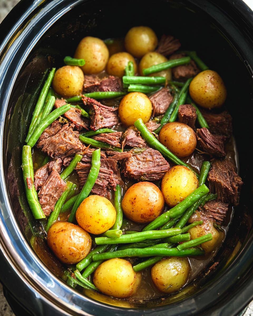 Overhead view of slow cooker garlic butter beef with potatoes and green beans.