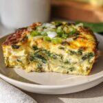 A slice of baked cottage cheese eggs with spinach and green onions on a plate, showcasing a protein-rich breakfast.