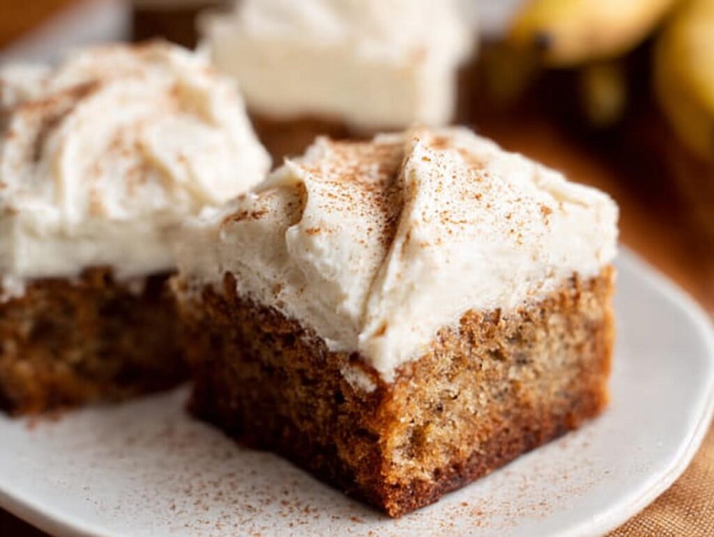 Close-up of a square Banana Bread Brownie Made Easy, topped with creamy frosting and a dusting of cinnamon.
