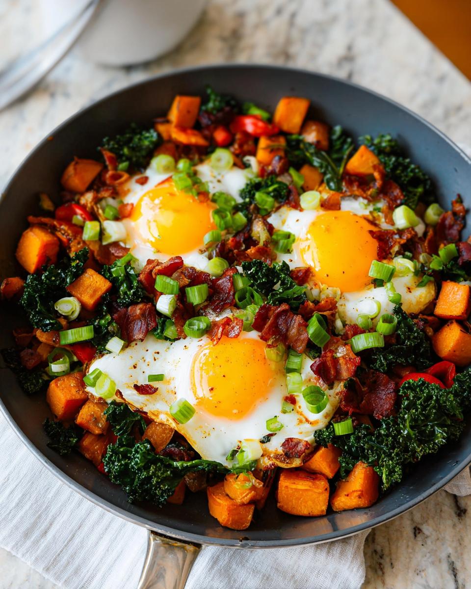 A close-up of a skillet filled with a BREAKFAST SWEET POTATO hash, topped with fried eggs, bacon, and green onions.