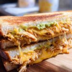 A close-up of a Chicken Avocado Melt Sandwich, showcasing melted cheese, shredded chicken, and avocado.