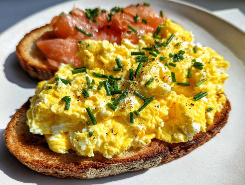 Close-up of Creamy Ricotta Egg Toast topped with scrambled eggs, chives, and smoked salmon.