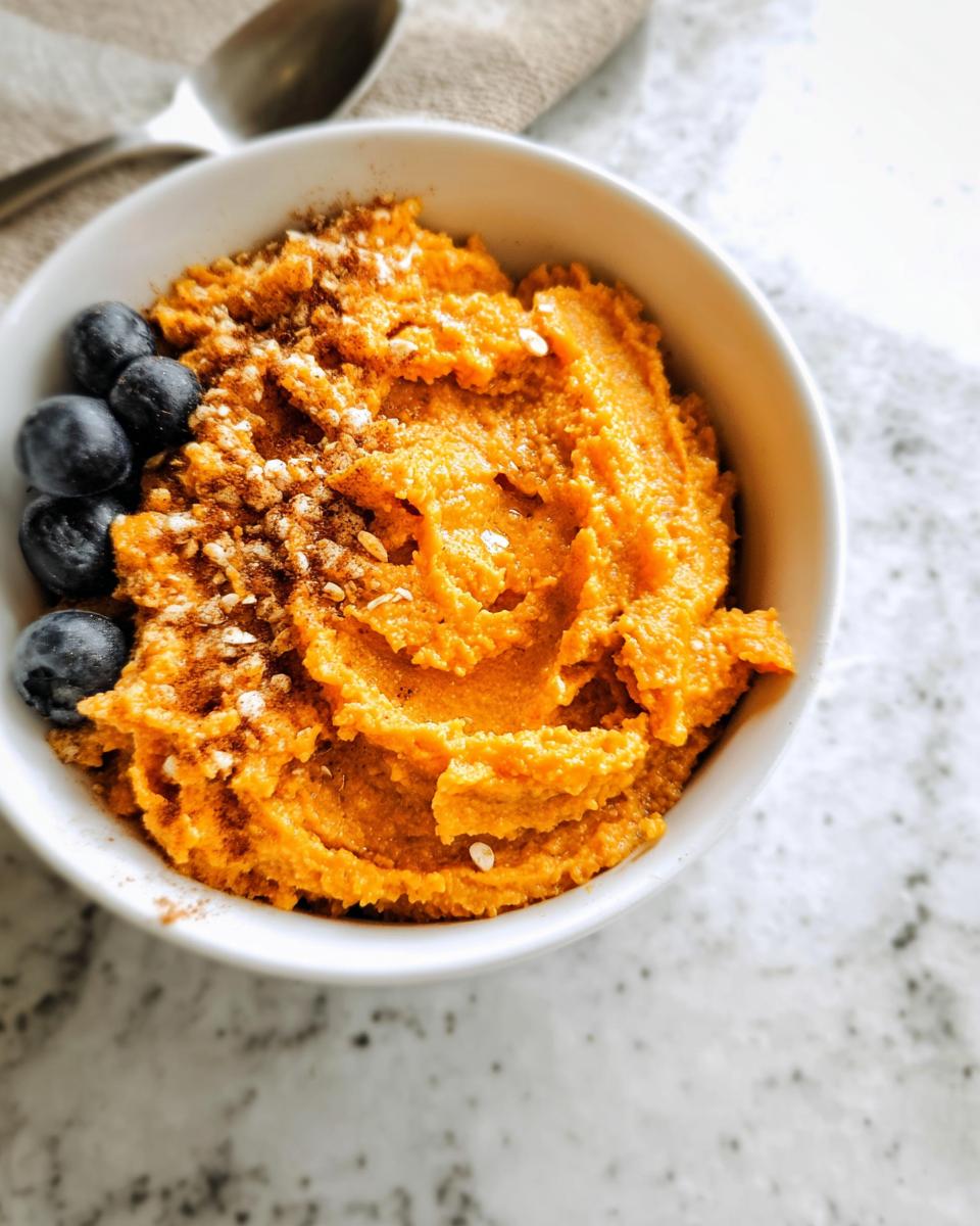 A close-up of a Delicious Sweet Potato Breakfast Bowl topped with blueberries and cinnamon.