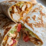 A delicious Easy Chipotle Ranch Grilled Chicken Burrito, cut in half to show the filling of chicken, cheese, lettuce, and tomato.