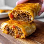 A close-up of a Grilled Cheese Burrito Made Easy, cut in half to reveal a hearty filling of seasoned ground beef and rice.