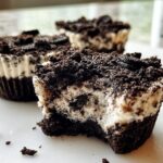 A close-up of a healthy no-bake Oreo cheesecake bite with a bite taken out, showing the creamy filling and chocolate crust.