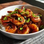 A bowl of glistening High-Protein Honey Garlic Shrimp served over white rice and garnished with chopped green onions.